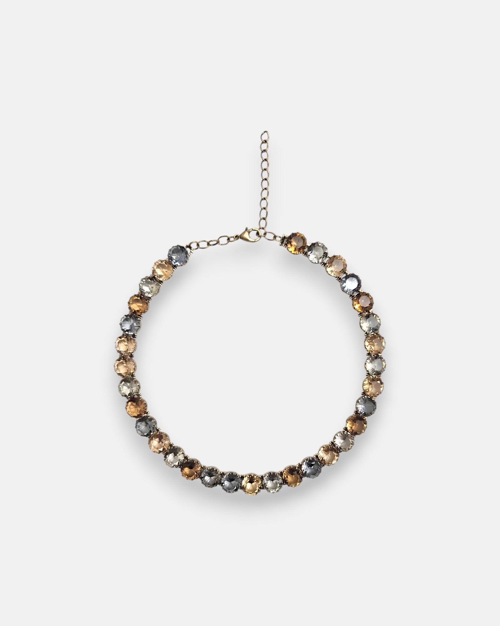 Collar corto estilo rivière de Tataborello extendido en círculo mostrando su hilera continua de cristales redondos facetados en tonos ahumados y ámbar con cierre de mosquetón.
