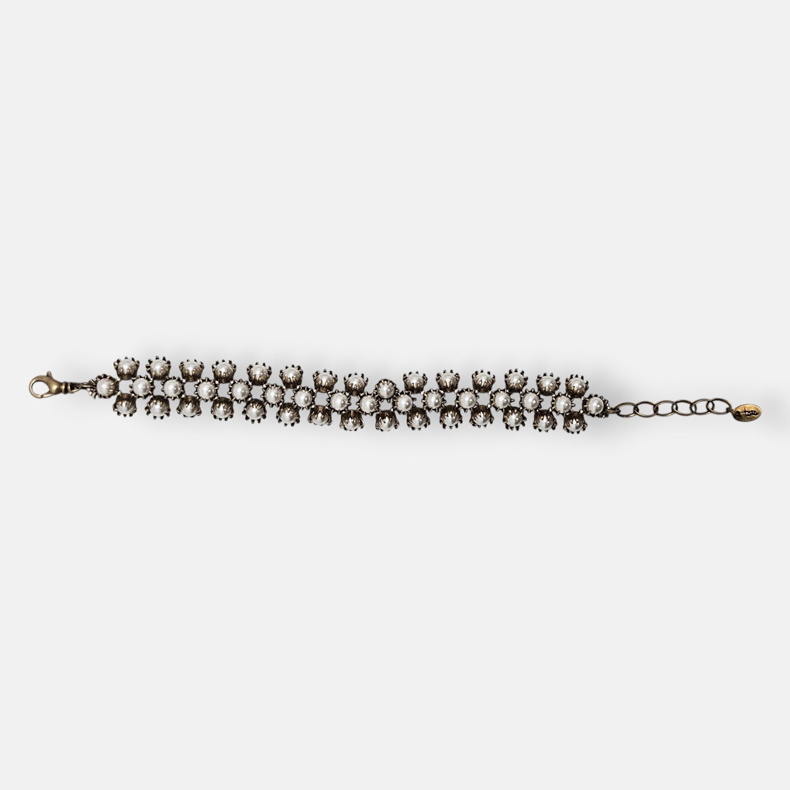 Pulsera Tataborello extendida con triple hilera de perlas y estructura de bronce antiguo.
