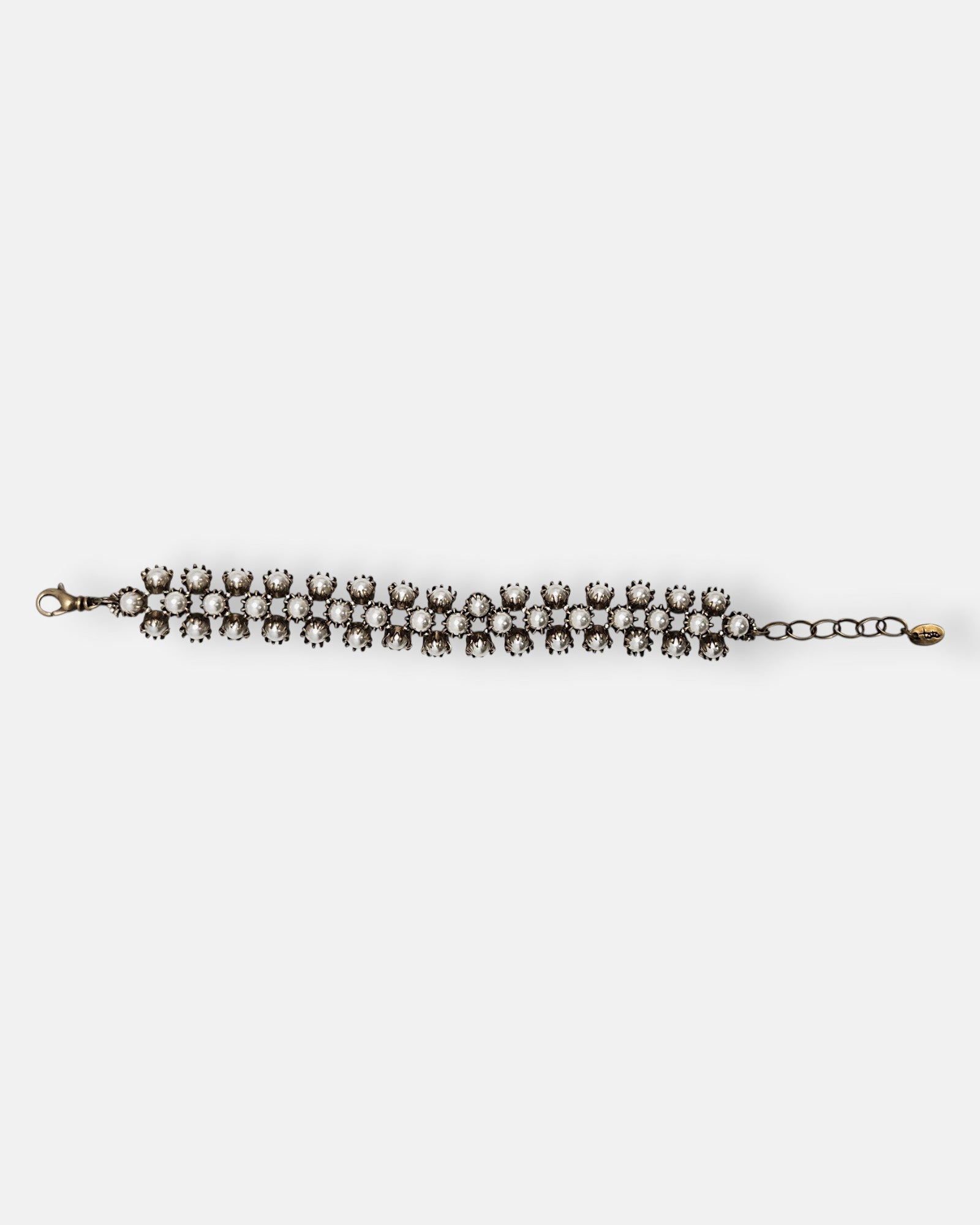 Pulsera Tataborello extendida con triple hilera de perlas y estructura de bronce antiguo.