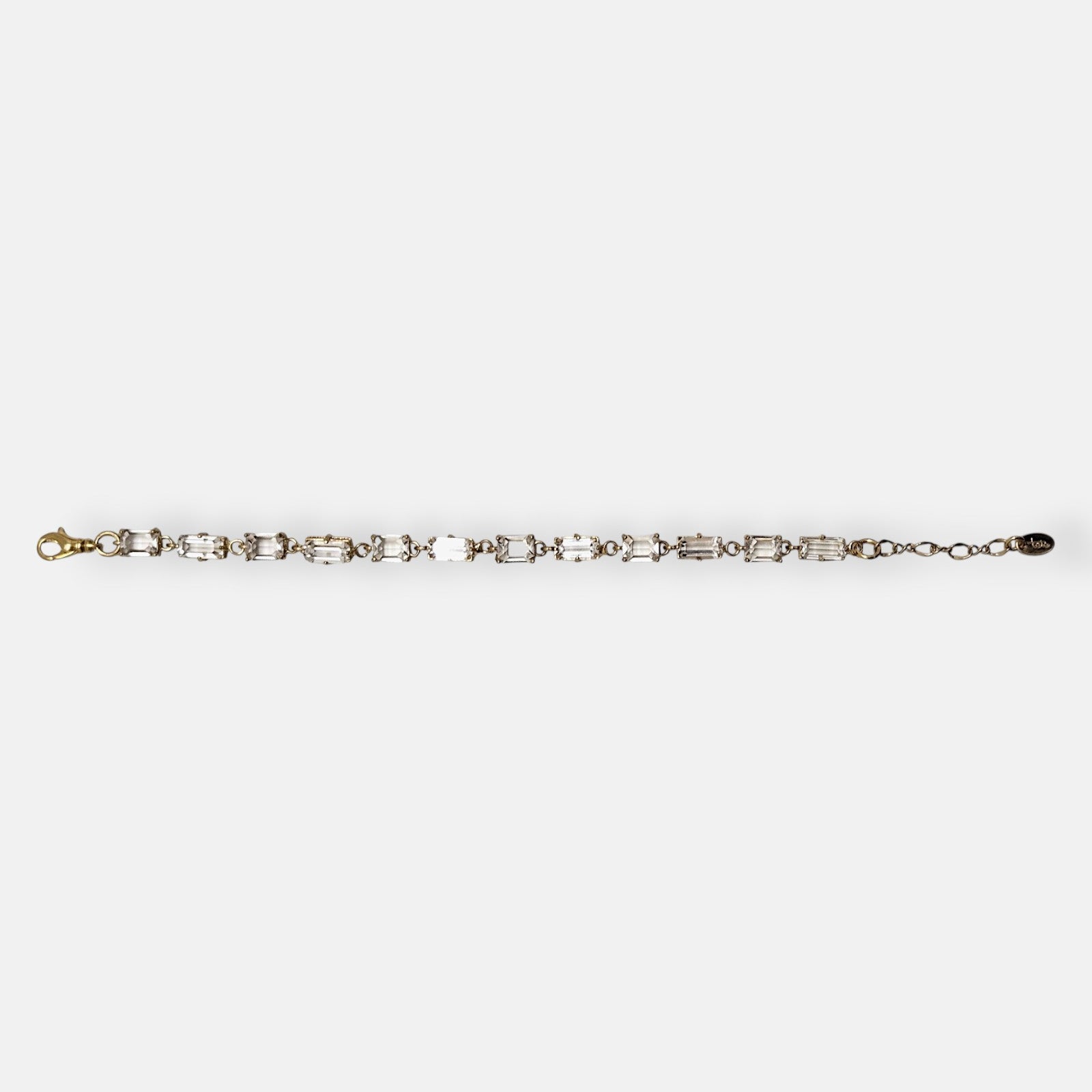 Pulsera Tataborello extendida con hilera de cristales rectangulares talla baguette y eslabones dorados.