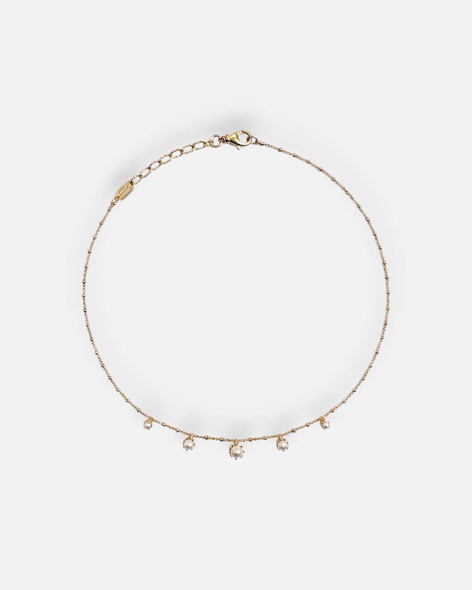 Collar de cadena fina dorada Tataborello extendido en círculo con cinco pequeñas perlas colgantes en la parte inferior y cierre ajustable de mosquetón.