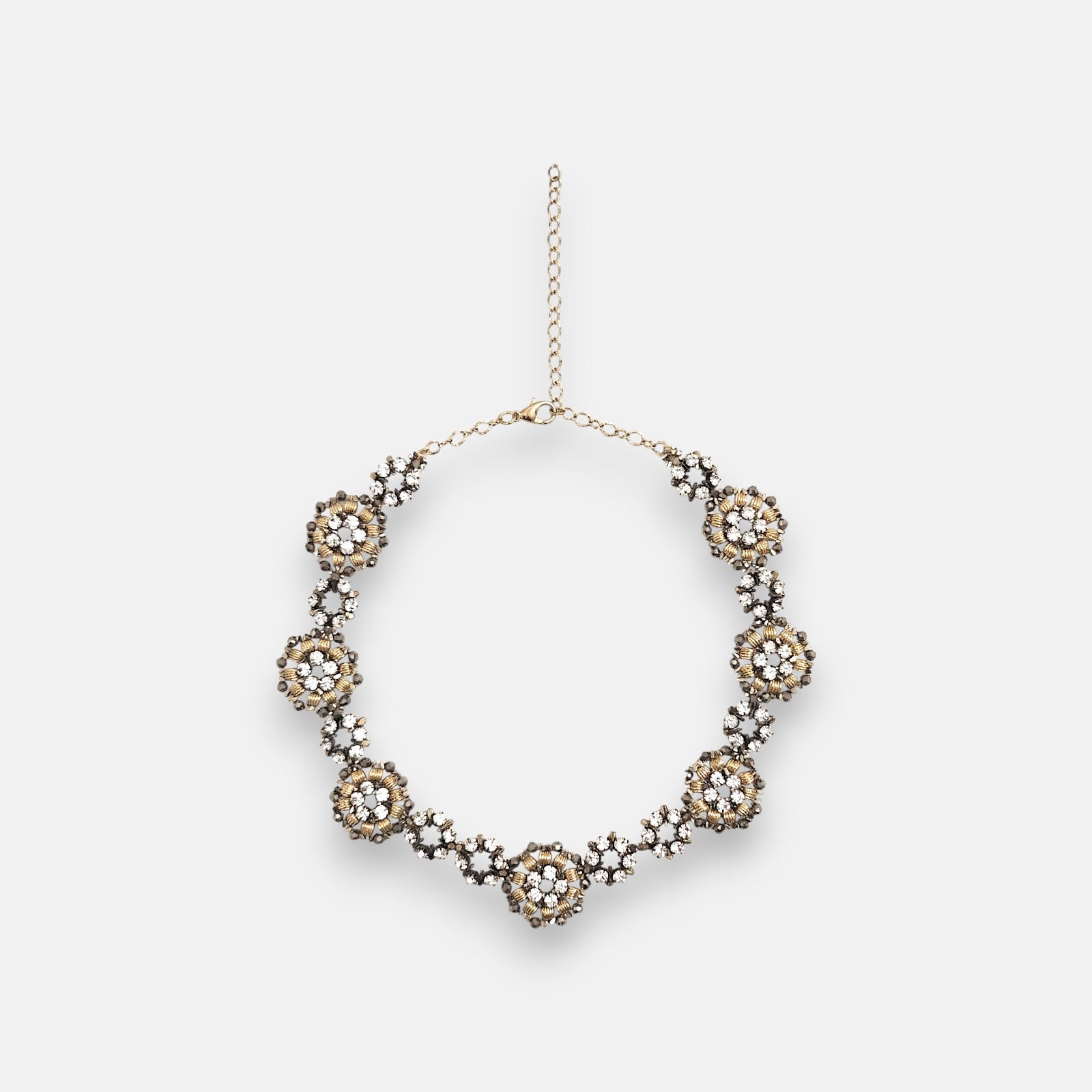 Collar gargantilla de flores Tataborello extendido en círculo mostrando su hilera continua de rosetones dorados con cristales y cadena de ajuste.