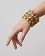 Vista del brazalete ancho "Jardín Dorado" en la muñeca, destacando su silueta floral y formato maxi.