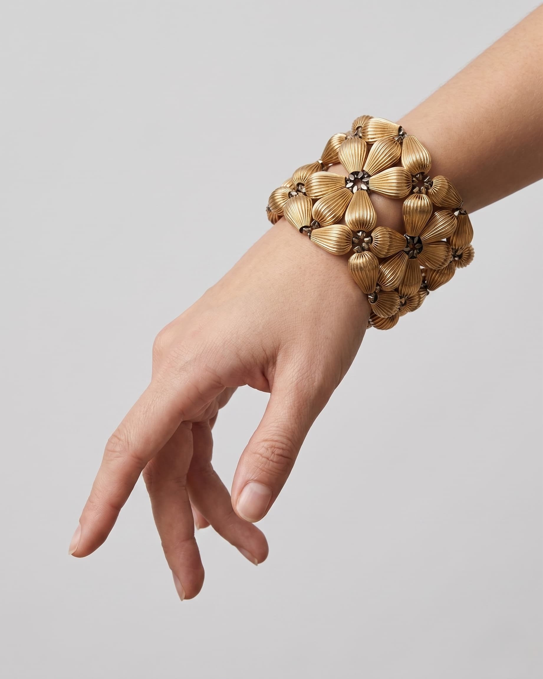 Vista del brazalete ancho "Jardín Dorado" en la muñeca, destacando su silueta floral y formato maxi.