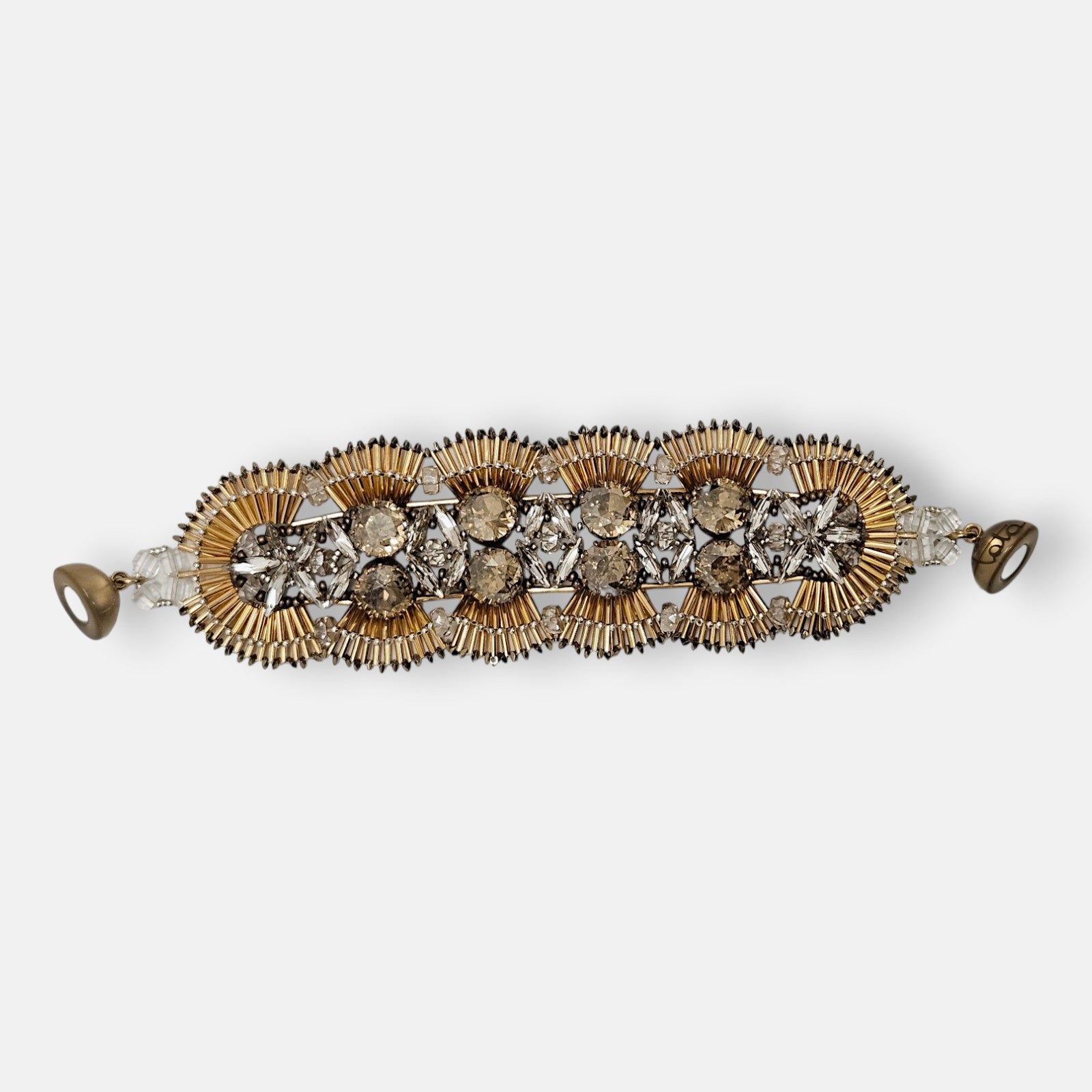 Maxi pulsera ancha Tataborello extendida con eslabones en forma de abanicos dorados, cristales y cierre magnético.