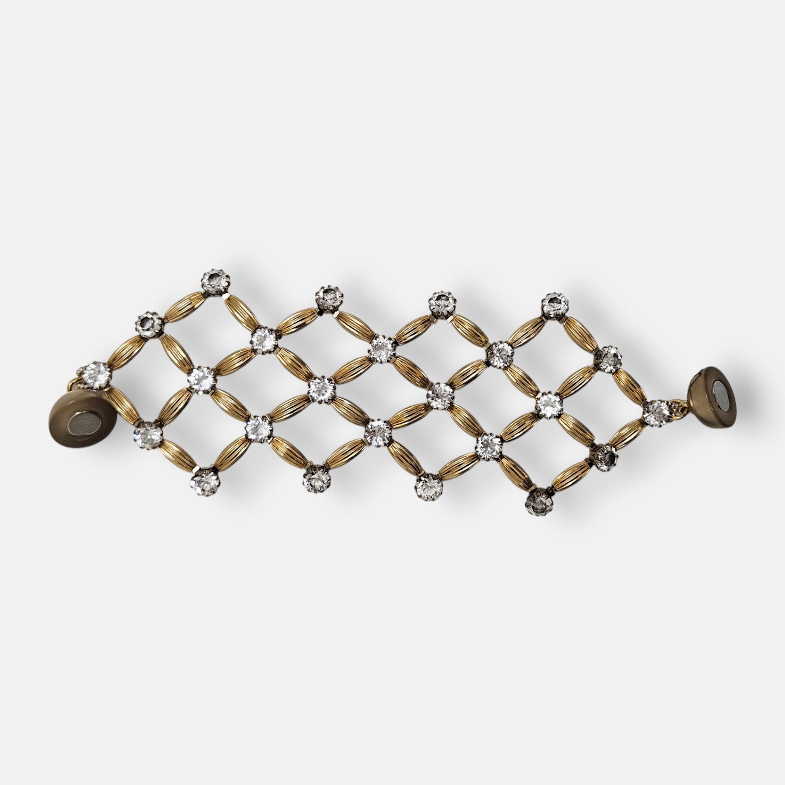 Maxi pulsera ancha Tataborello extendida con un diseño geométrico de red en oro y cristales con cierre de imán.