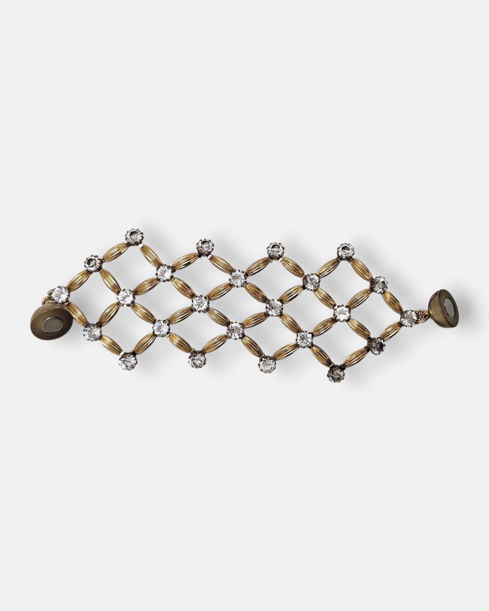 Maxi pulsera ancha Tataborello extendida con un diseño geométrico de red en oro y cristales con cierre de imán.