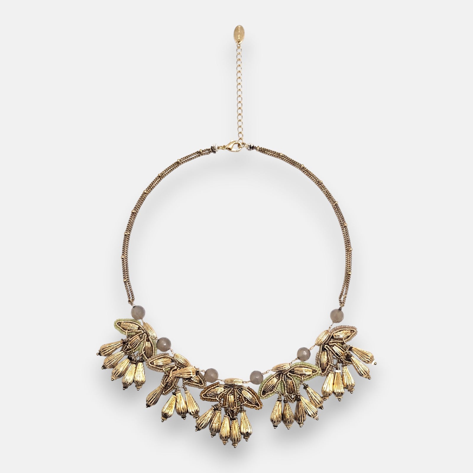 Collar pechera maximalista Tataborello extendido en círculo mostrando su frontal de hojas doradas colgantes, cuentas grises y cordón multifila.