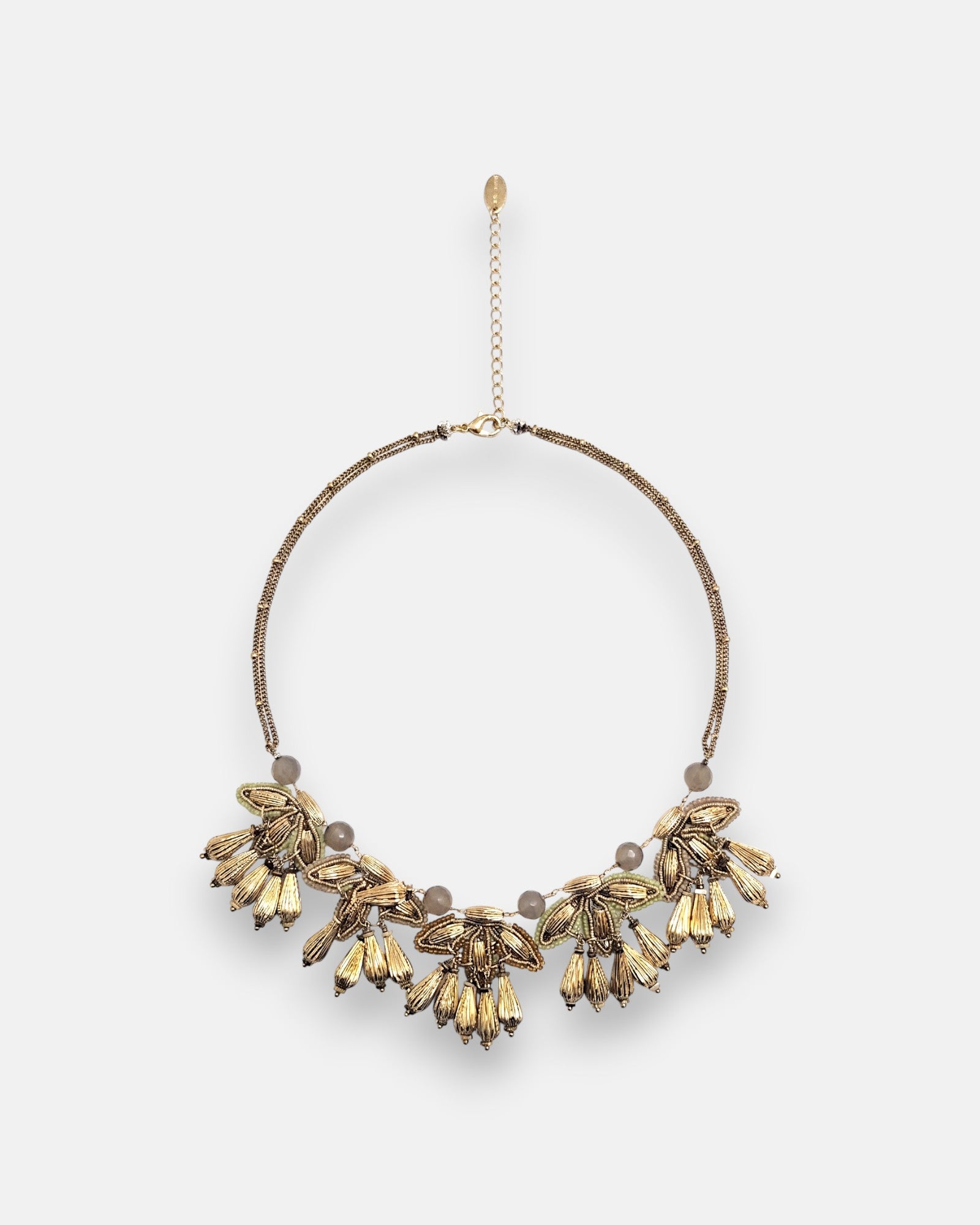 Collar pechera maximalista Tataborello extendido en círculo mostrando su frontal de hojas doradas colgantes, cuentas grises y cordón multifila.