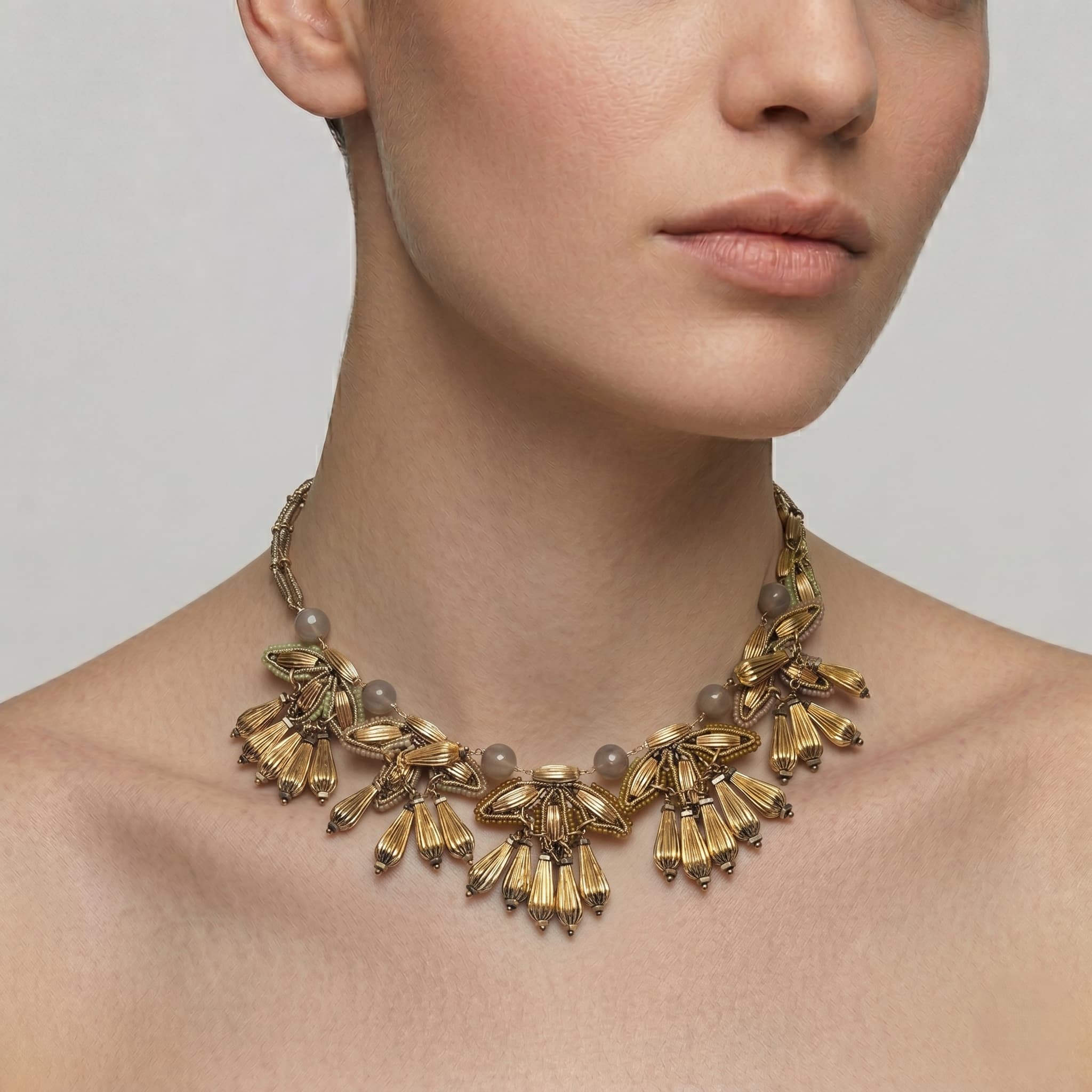 Vista de una modelo portando el collar pechera de diseño orgánico Follaje Imperial de Tataborello, destacando el volumen de las piezas doradas sobre el cuello.