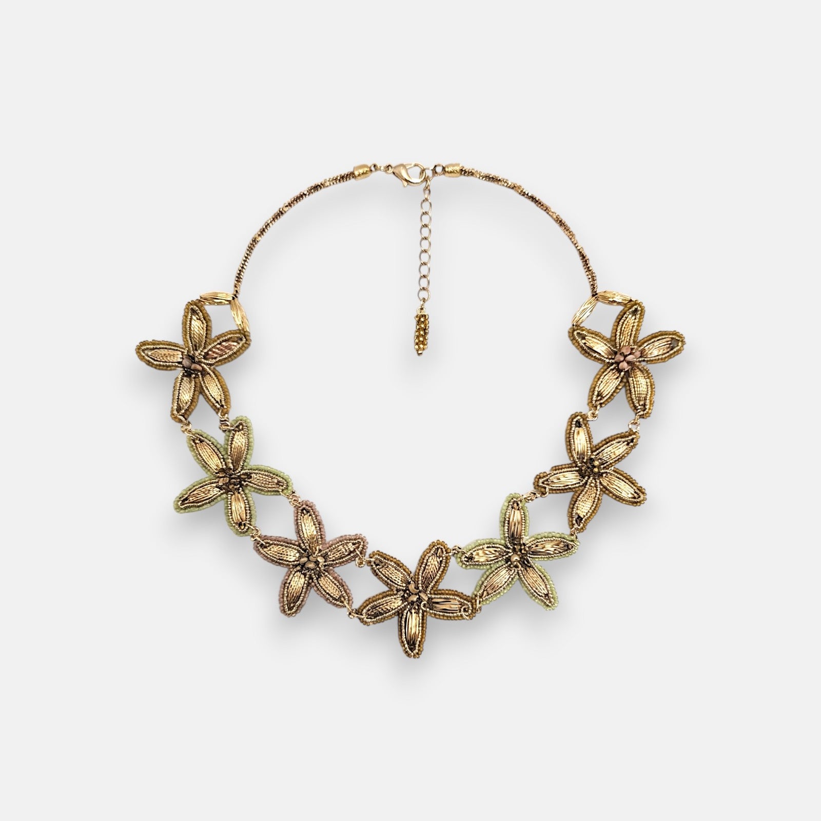 Collar pechera máxi de Tataborello extendido en círculo mostrando su imponente frontal de hojas doradas colgantes, cuentas grises y cordón multifila.