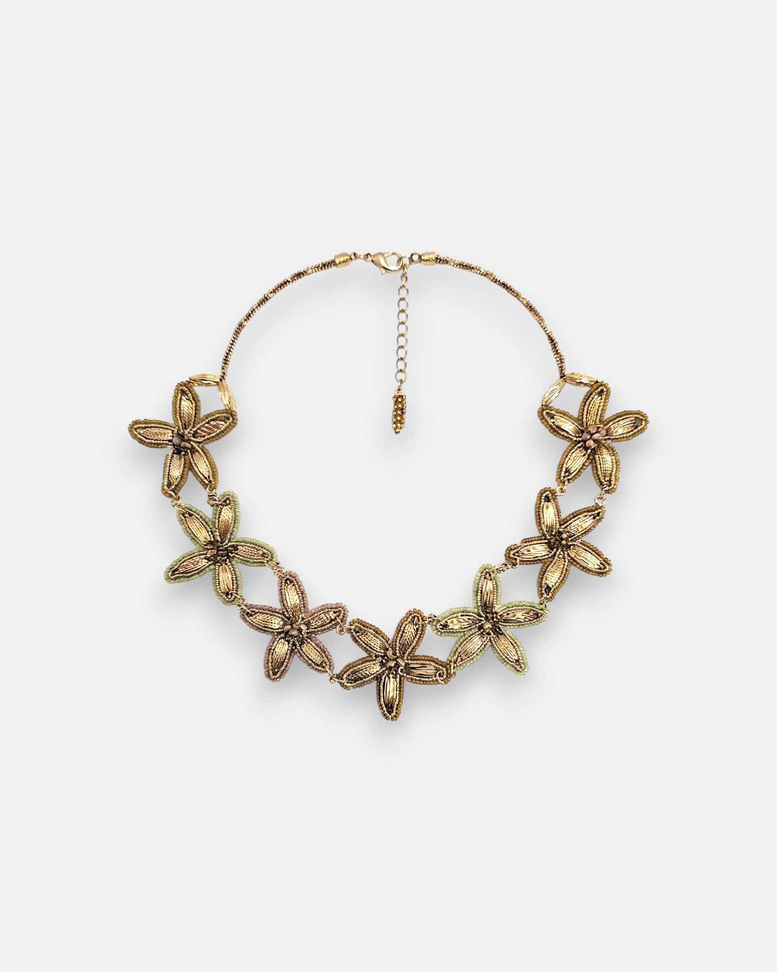 Collar pechera máxi de Tataborello extendido en círculo mostrando su imponente frontal de hojas doradas colgantes, cuentas grises y cordón multifila.