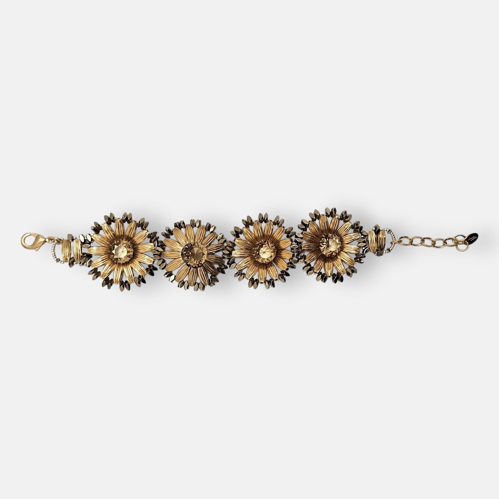 : Pulsera Tataborello extendida compuesta por cuatro grandes eslabones en forma de flor dorada y cristales ámbar.