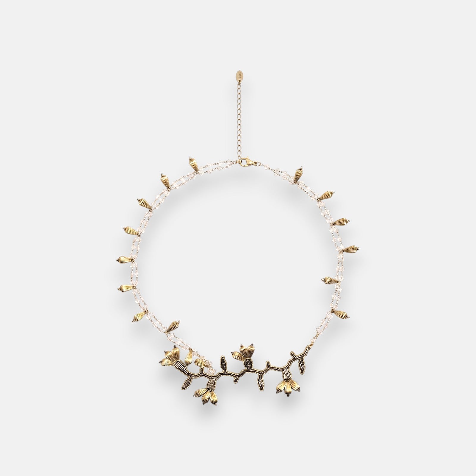 Collar pechera de gran volumen Tataborello extendido en círculo mostrando su base de hilos negros, bordado central de cristales y piedras grises.