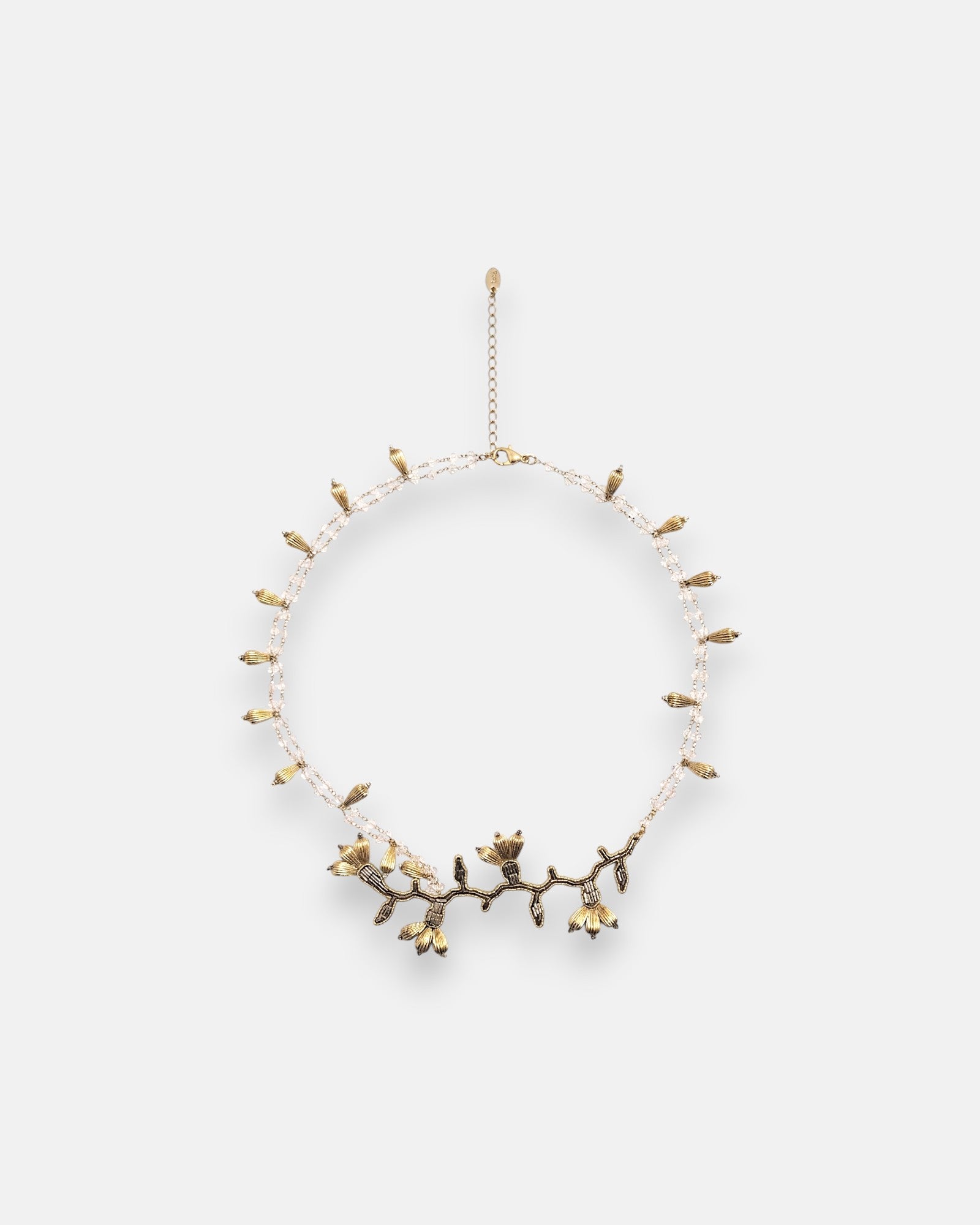 Collar pechera de gran volumen Tataborello extendido en círculo mostrando su base de hilos negros, bordado central de cristales y piedras grises.