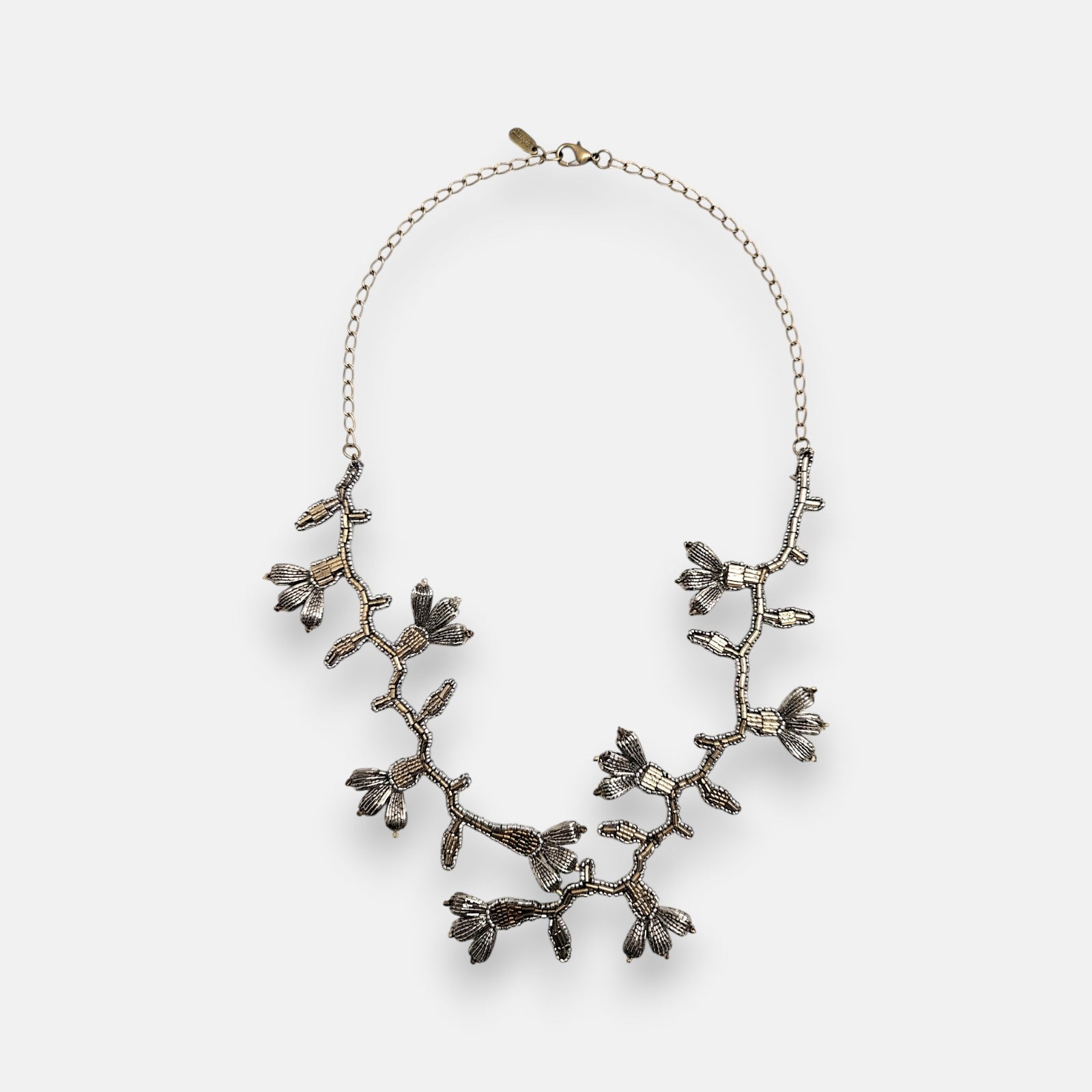 Collar pechera largo Tataborello extendido en círculo mostrando su compleja estructura de enredadera botánica tejida con cuentas de plata vieja y oro.
