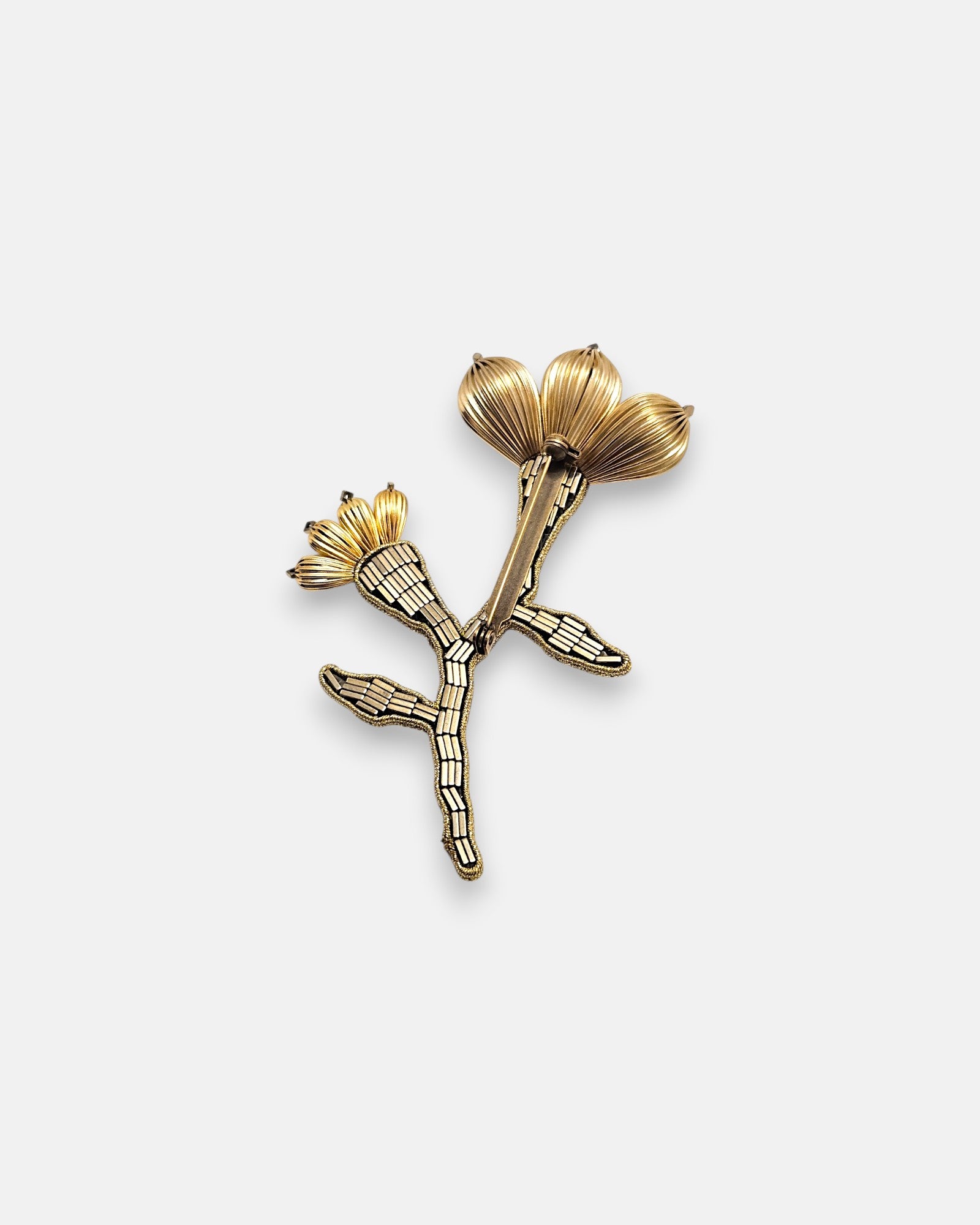 Broche artesanal de solapa Tataborello con silueta de flor y rama bordada en canutillos bronce y pétalos de oro estriados.