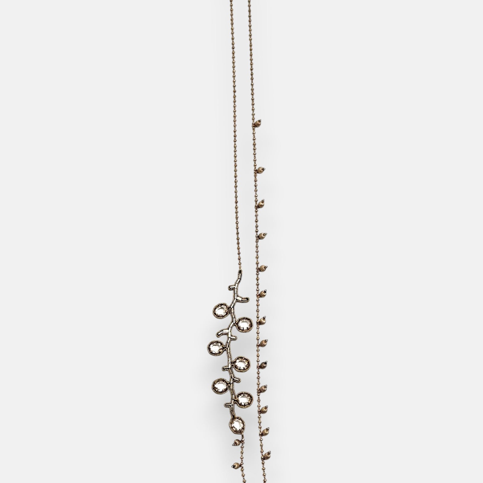 Collar largo sautoir Tataborello extendido en vertical mostrando su cadena fina de bolitas doradas con dijes colgantes y una rama lateral de cristales.