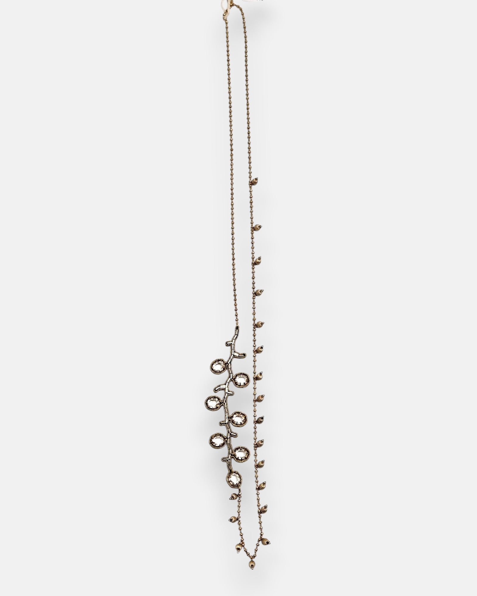 Collar largo sautoir Tataborello extendido en vertical mostrando su cadena fina de bolitas doradas con dijes colgantes y una rama lateral de cristales.