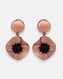 pareja de pendientes colgantes de tamaño mini con silueta de flor de amapola de Ciléa Paris, destacando sus pétalos de resina en color rosa polvo brillante, un centro negro texturizado que simula los estambres y un botón superior esférico a juego.