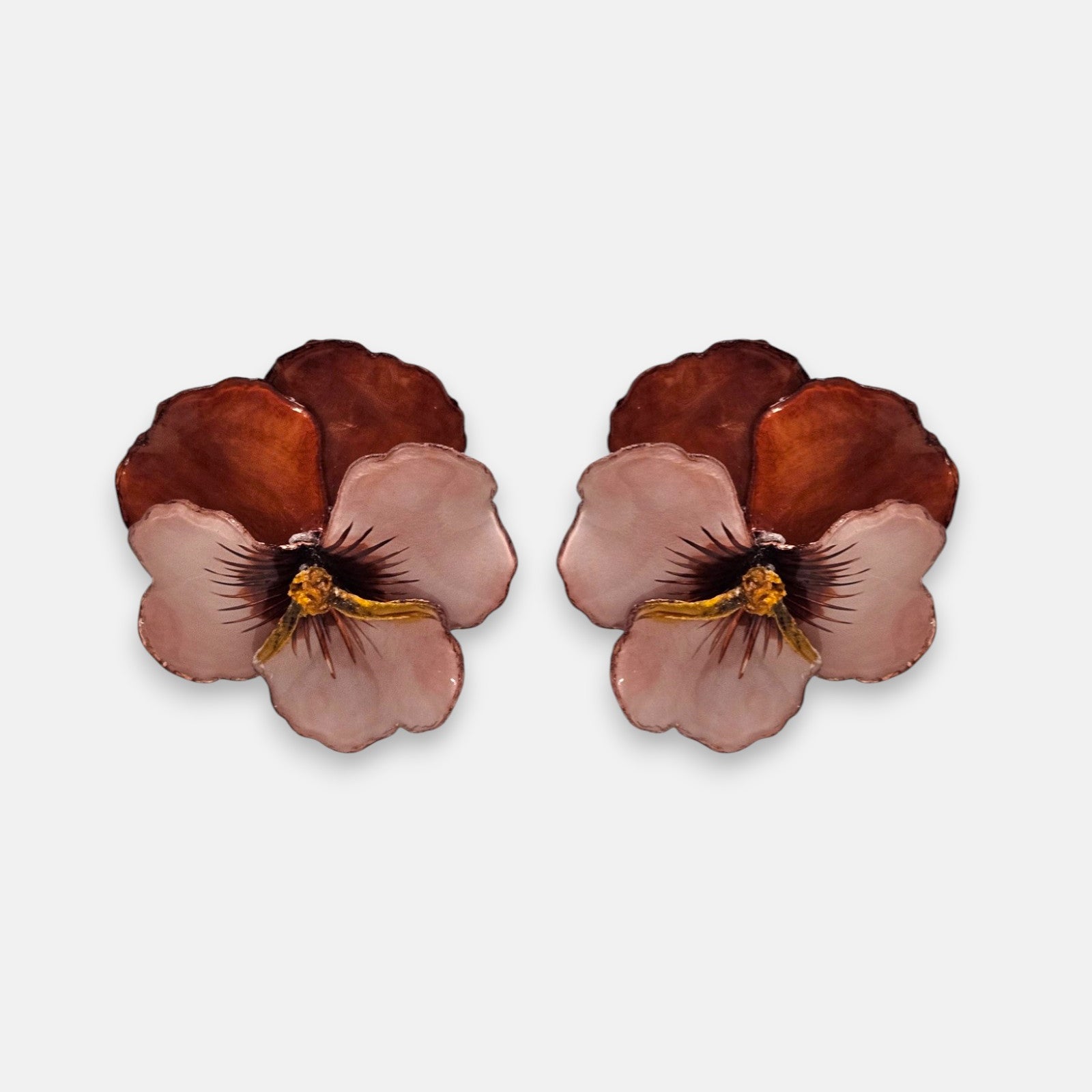 pareja de pendientes con forma de flor de pensamiento de Ciléa Paris, destacando sus pétalos superiores marrón caramelo y sus pétalos inferiores rosa claro.