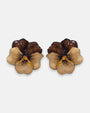 pareja de pendientes con forma de flor de pensamiento de Ciléa Paris, destacando sus pétalos superiores marrón caramelo y sus pétalos inferiores rosa claro.