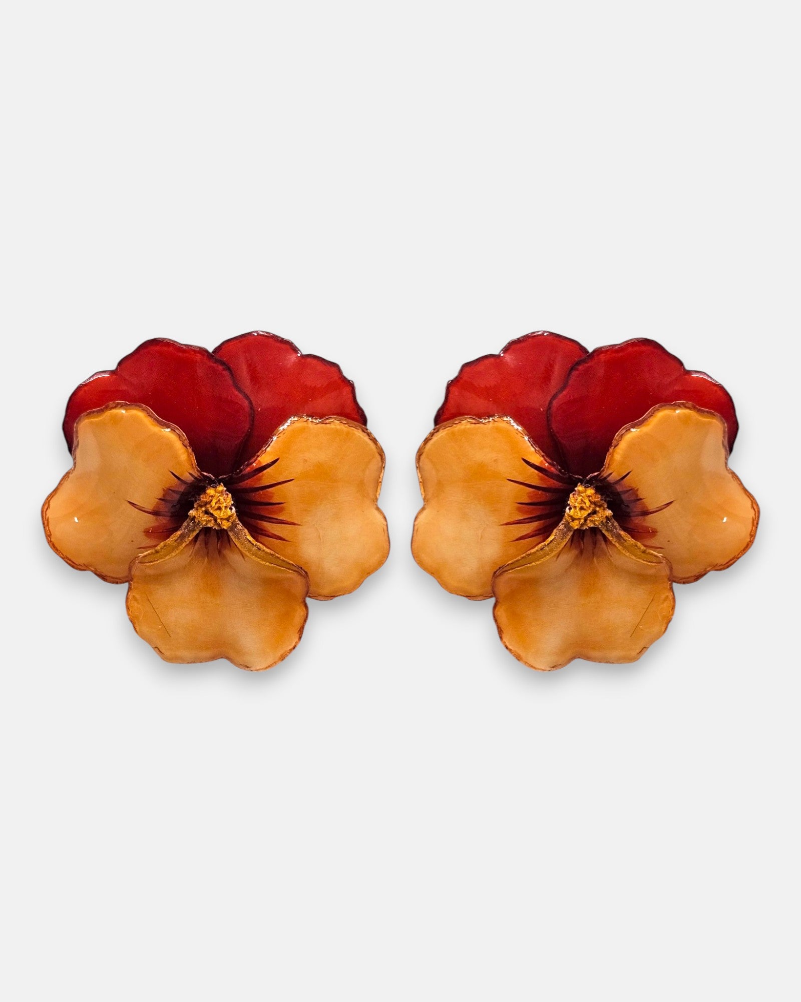 pareja de pendientes con forma de flor de pensamiento de Ciléa Paris, destacando sus pétalos superiores rojo borgoña y sus pétalos inferiores en tono ocre o melocotón brillante.