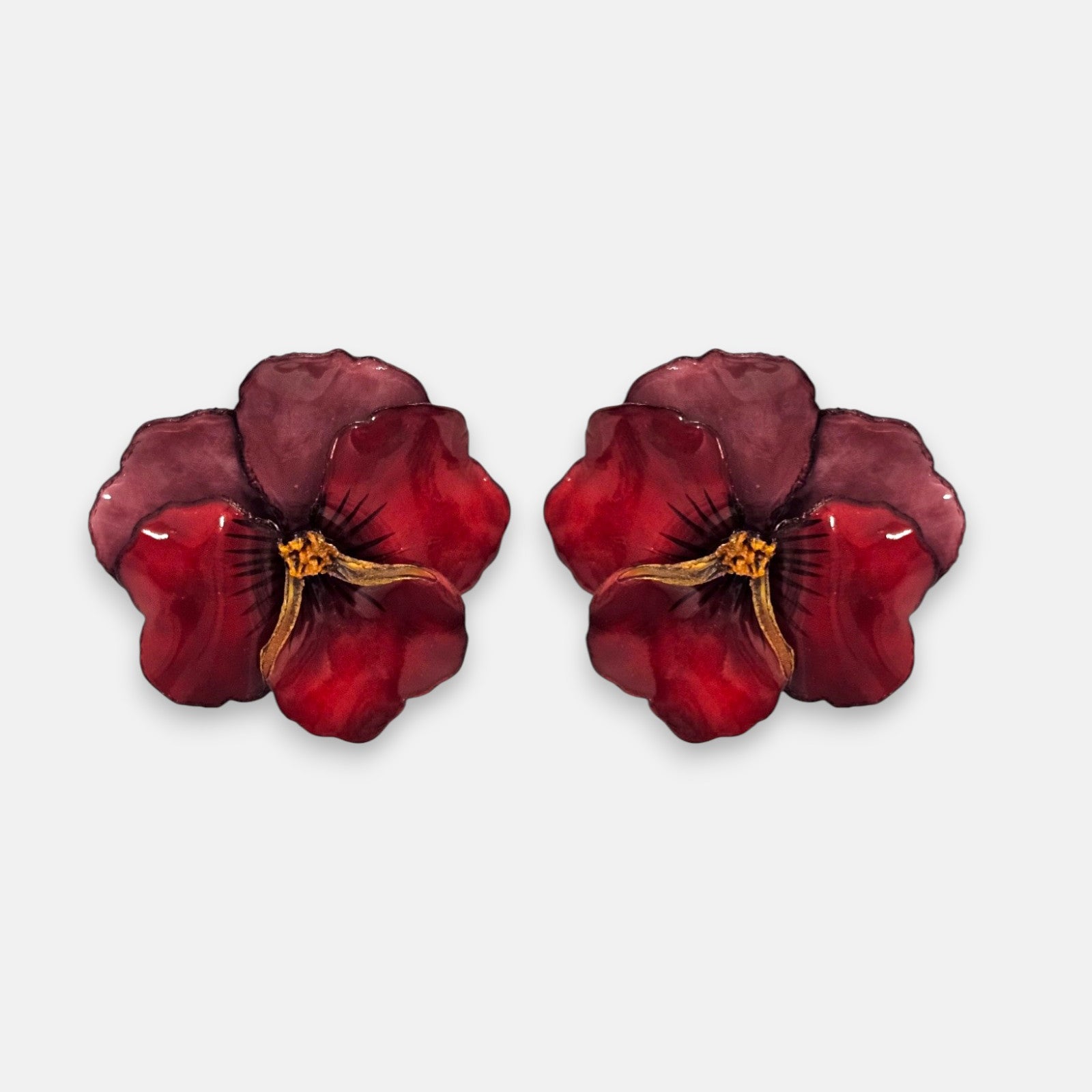 pareja de pendientes con forma de flor de pensamiento de Ciléa Paris, destacando sus pétalos superiores en color ciruela oscuro y sus pétalos inferiores en rojo brillante.