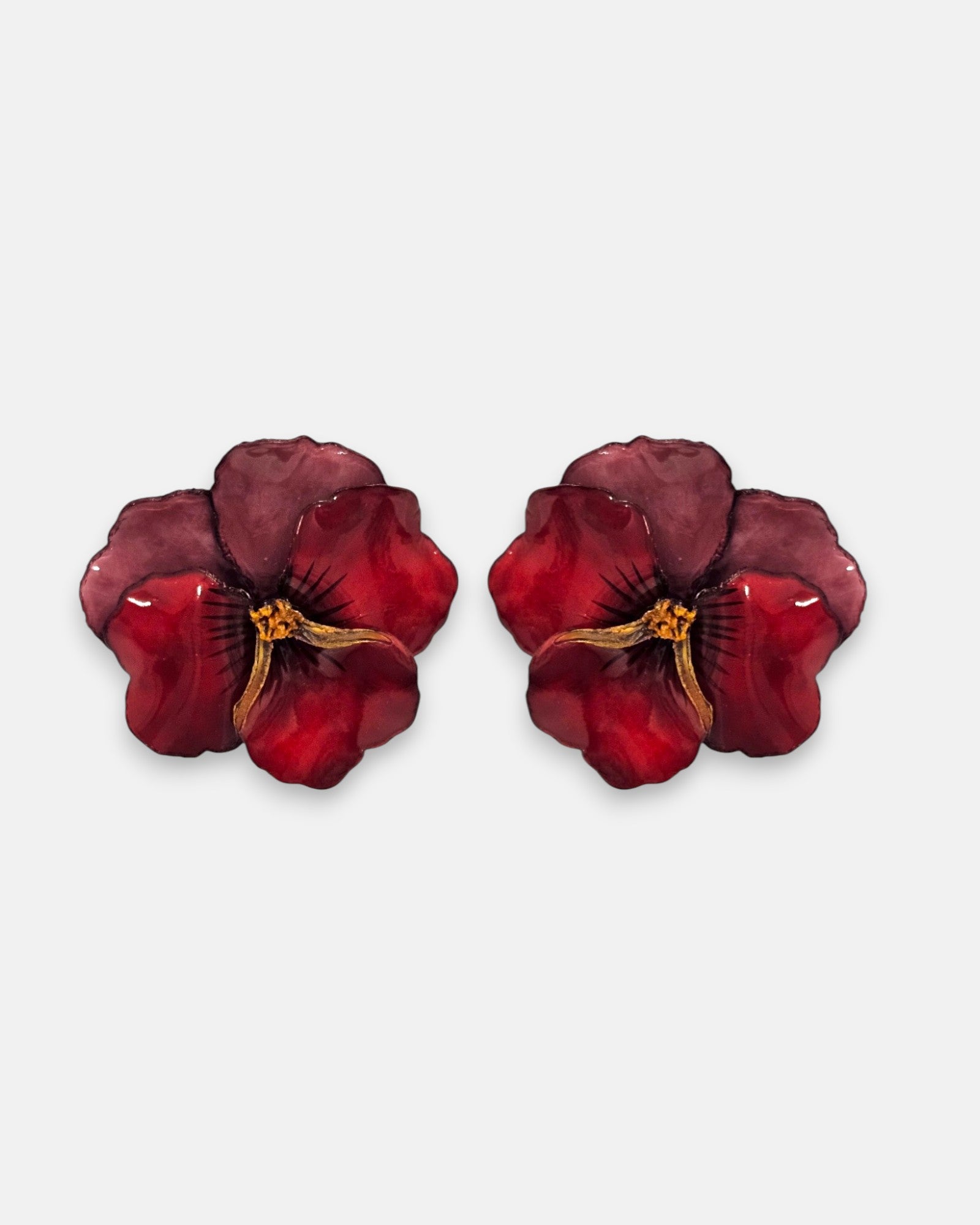 pareja de pendientes con forma de flor de pensamiento de Ciléa Paris, destacando sus pétalos superiores en color ciruela oscuro y sus pétalos inferiores en rojo brillante.