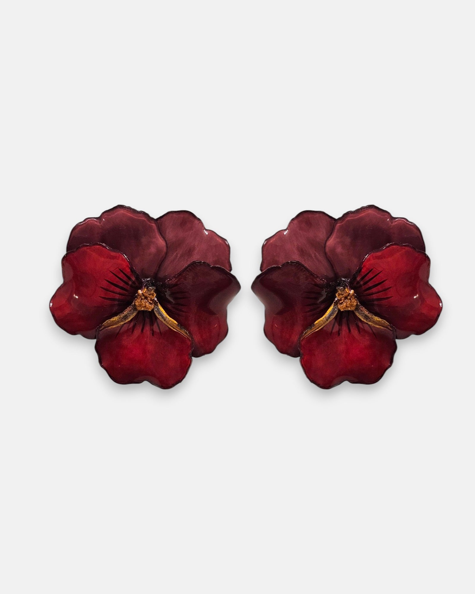 pareja de pendientes con forma de flor de pensamiento de Ciléa Paris, destacando sus pétalos superiores en color ciruela oscuro y sus pétalos inferiores en rojo brillante con acabado pulido.