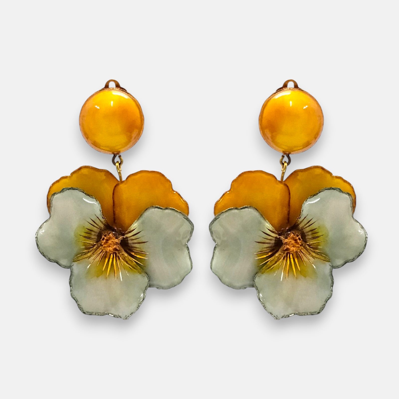 pareja de pendientes colgantes maxi con forma de flor de pensamiento de Ciléa Paris, destacando sus pétalos superiores en color ocre ámbar, pétalos inferiores verde menta suave y un gran botón superior esférico amarillo a juego.