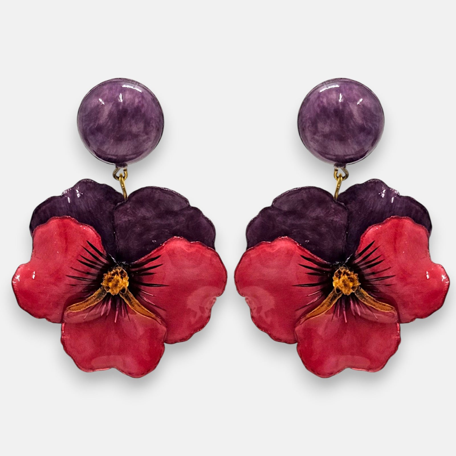 pareja de pendientes colgantes maxi con forma de flor de pensamiento de Ciléa Paris, destacando sus pétalos superiores en color violeta oscuro, pétalos inferiores en rojo rubí brillante y un gran botón superior esférico a juego.