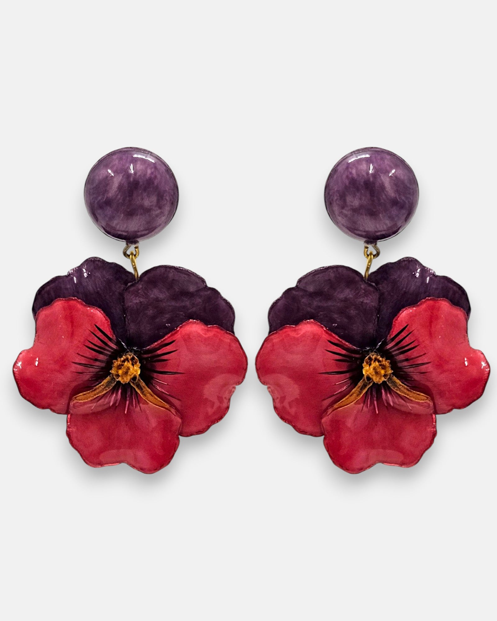 pareja de pendientes colgantes maxi con forma de flor de pensamiento de Ciléa Paris, destacando sus pétalos superiores en color violeta oscuro, pétalos inferiores en rojo rubí brillante y un gran botón superior esférico a juego.