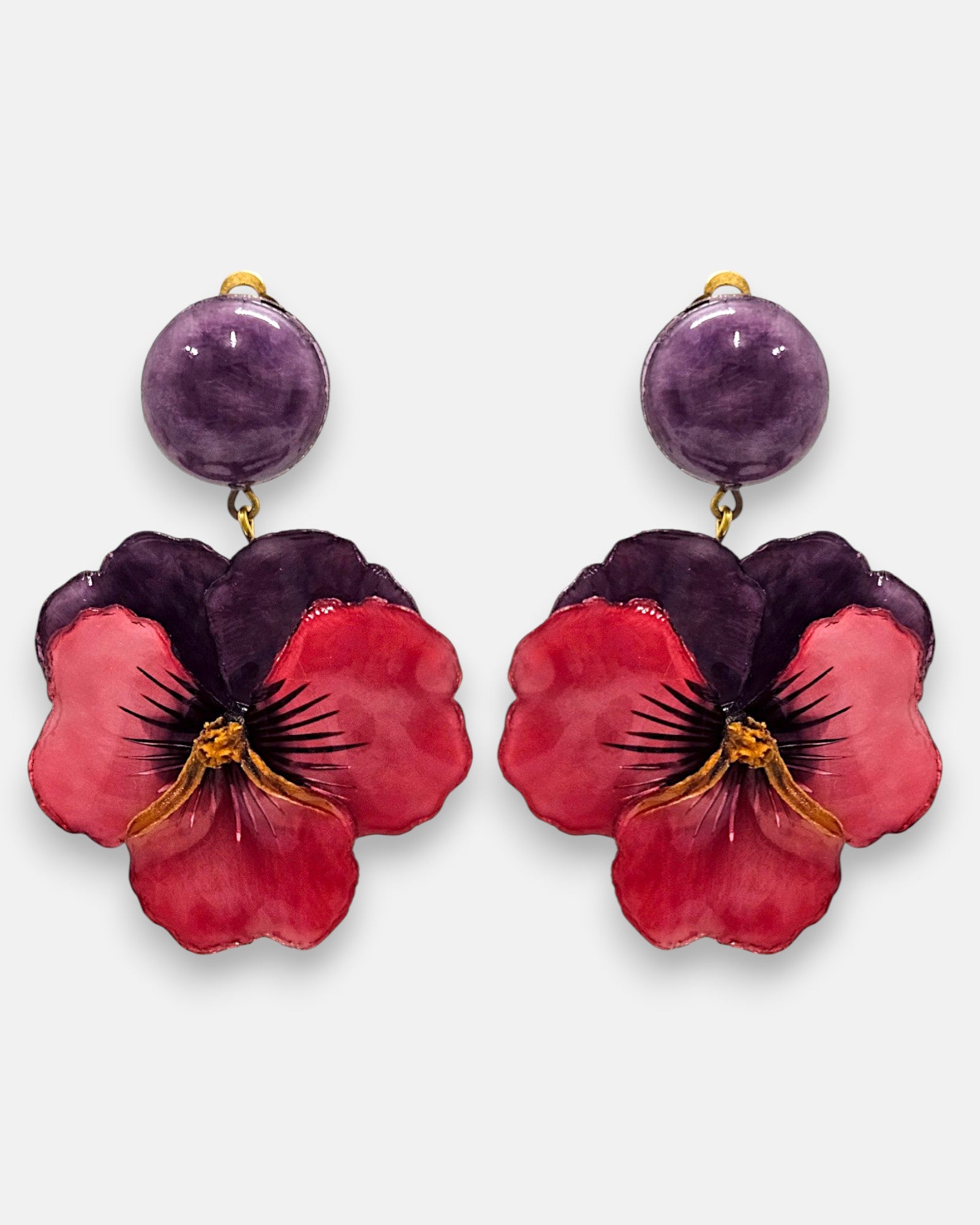 pareja de pendientes colgantes maxi con forma de flor de pensamiento de Ciléa Paris, destacando sus pétalos superiores en color violeta oscuro, pétalos inferiores en rojo rubí brillante y un gran botón superior esférico a juego con enganche de pinza.