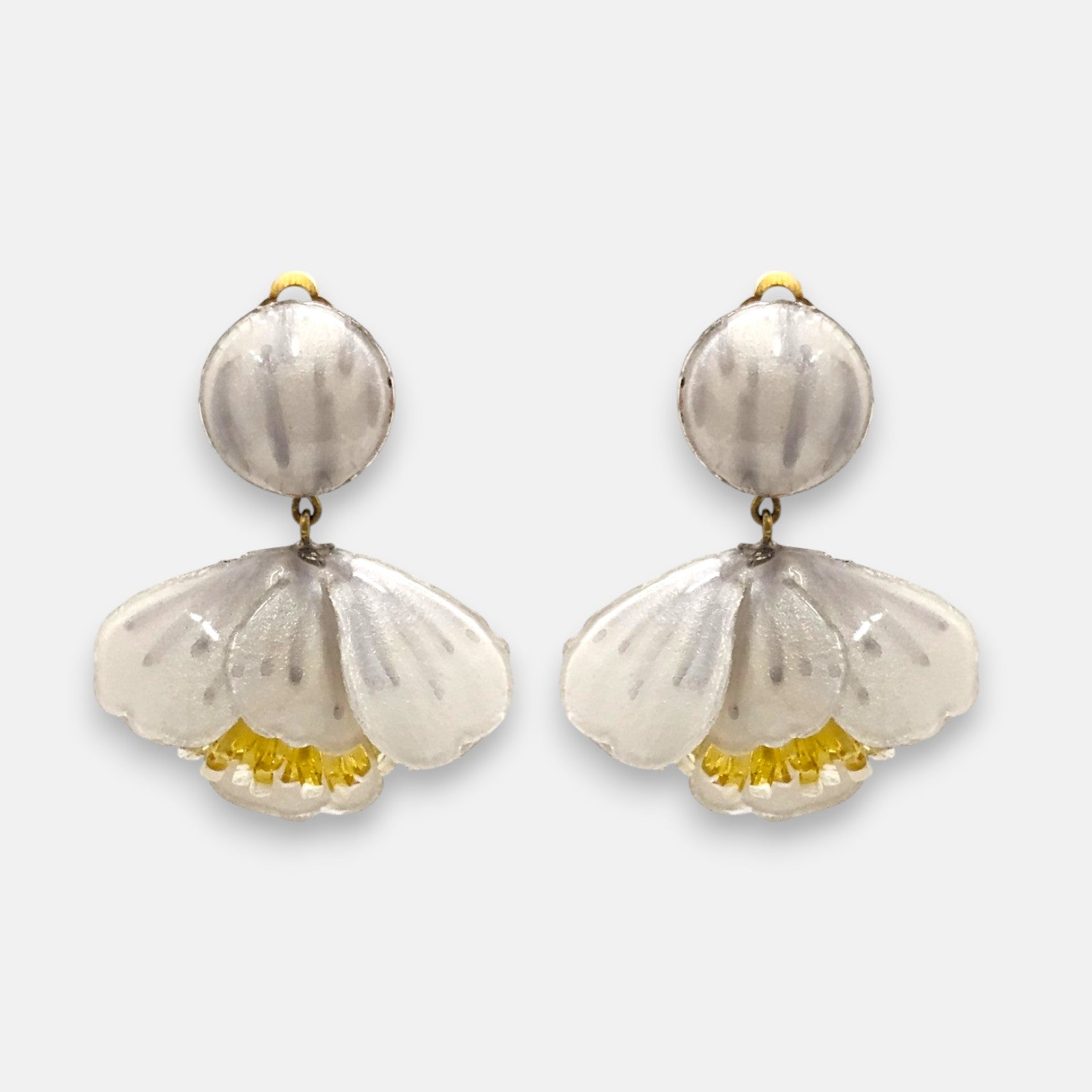 pareja de pendientes colgantes con silueta de flor de tulipán de Ciléa Paris, destacando sus pétalos de resina en color blanco nácar brillante, pistilos amarillos inferiores expuestos y un gran botón superior esférico de pinza coordinado.
