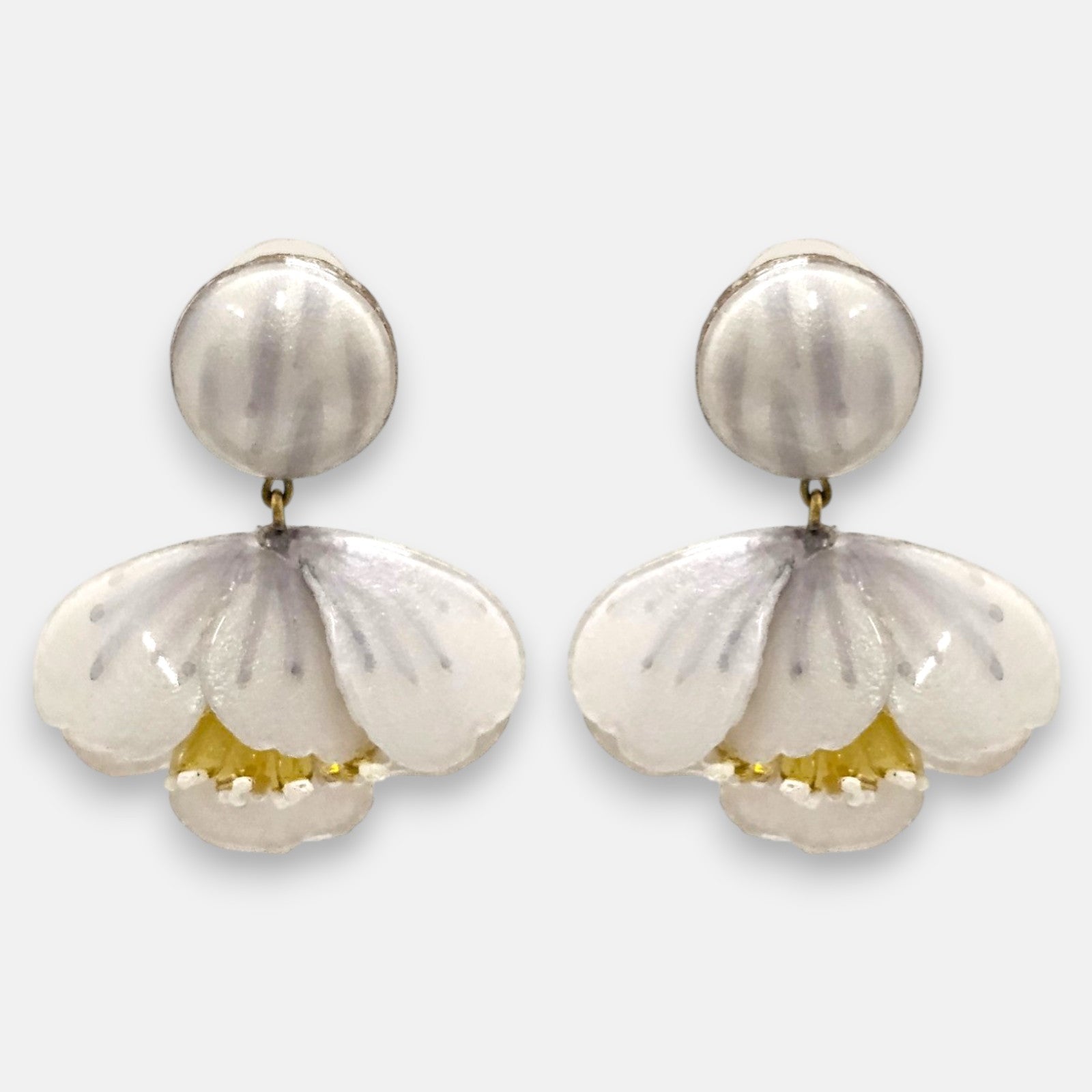 pareja de pendientes colgantes con silueta de flor de tulipán de Ciléa Paris, destacando sus pétalos de resina en color blanco nácar brillante, pistilos amarillos inferiores expuestos y un gran botón superior esférico de perno coordinado.