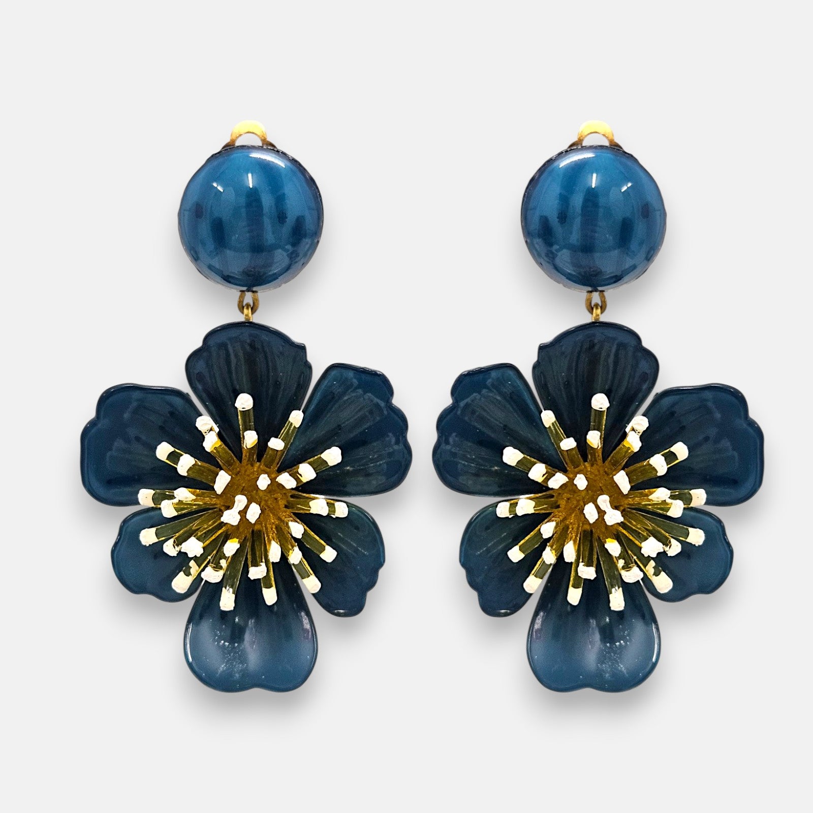 pareja de pendientes colgantes maxi con forma de flor de anémona de Ciléa Paris, destacando sus pétalos de resina en color azul petróleo brillante, un complejo centro de pistilos dorados con puntas blancas y un botón superior esférico a juego.