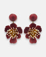 pareja de pendientes colgantes maxi con forma de flor de anémona de Ciléa Paris, destacando sus pétalos de resina en color rojo burdeos oscuro, un complejo centro de pistilos dorados con puntas blancas y un botón superior esférico de perno coordinado.