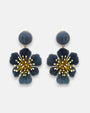 pareja de pendientes colgantes maxi con forma de flor de anémona de Ciléa Paris, destacando sus pétalos de resina en color gris antracita oscuro, un complejo centro de pistilos dorados con puntas blancas y un botón superior esférico a juego.