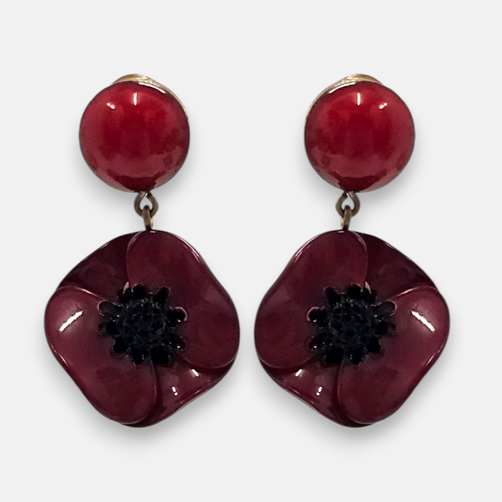 pareja de pendientes colgantes mini con silueta de flor de amapola de Ciléa Paris, destacando sus pétalos de resina en color rojo burdeos brillante, el centro negro texturizado que emula los estambres y un botón superior esférico de perno coordinado.