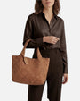 modelo luciendo en el antebrazo el Bolso Tote Intrecciato Cognac de Plinio Visonà con camisa de seda oscura.