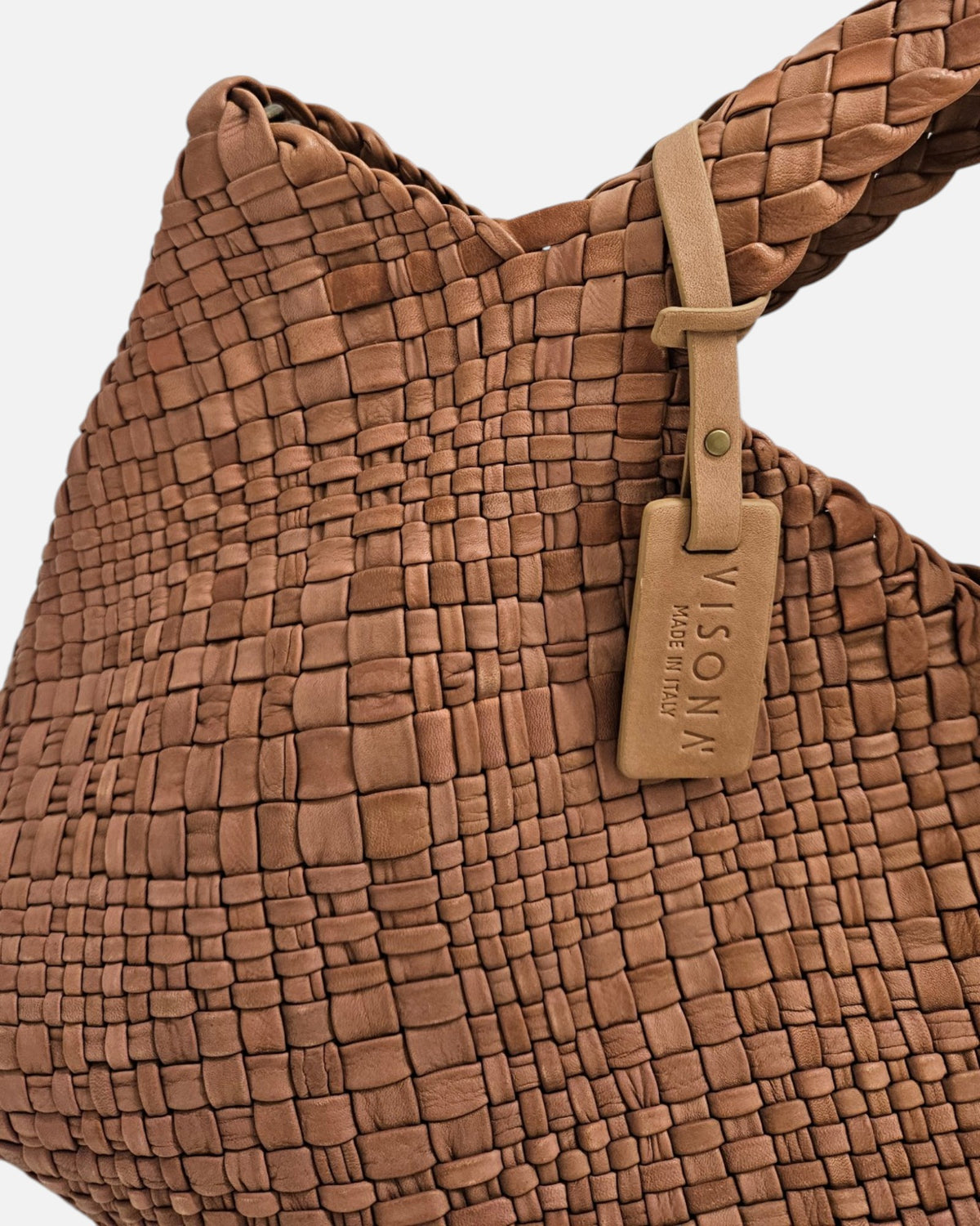 primer plano macro del entramado de piel del Bolso Tote Intrecciato Cognac de Plinio Visonà y la etiqueta con la inscripción "Visonà Made in Italy".