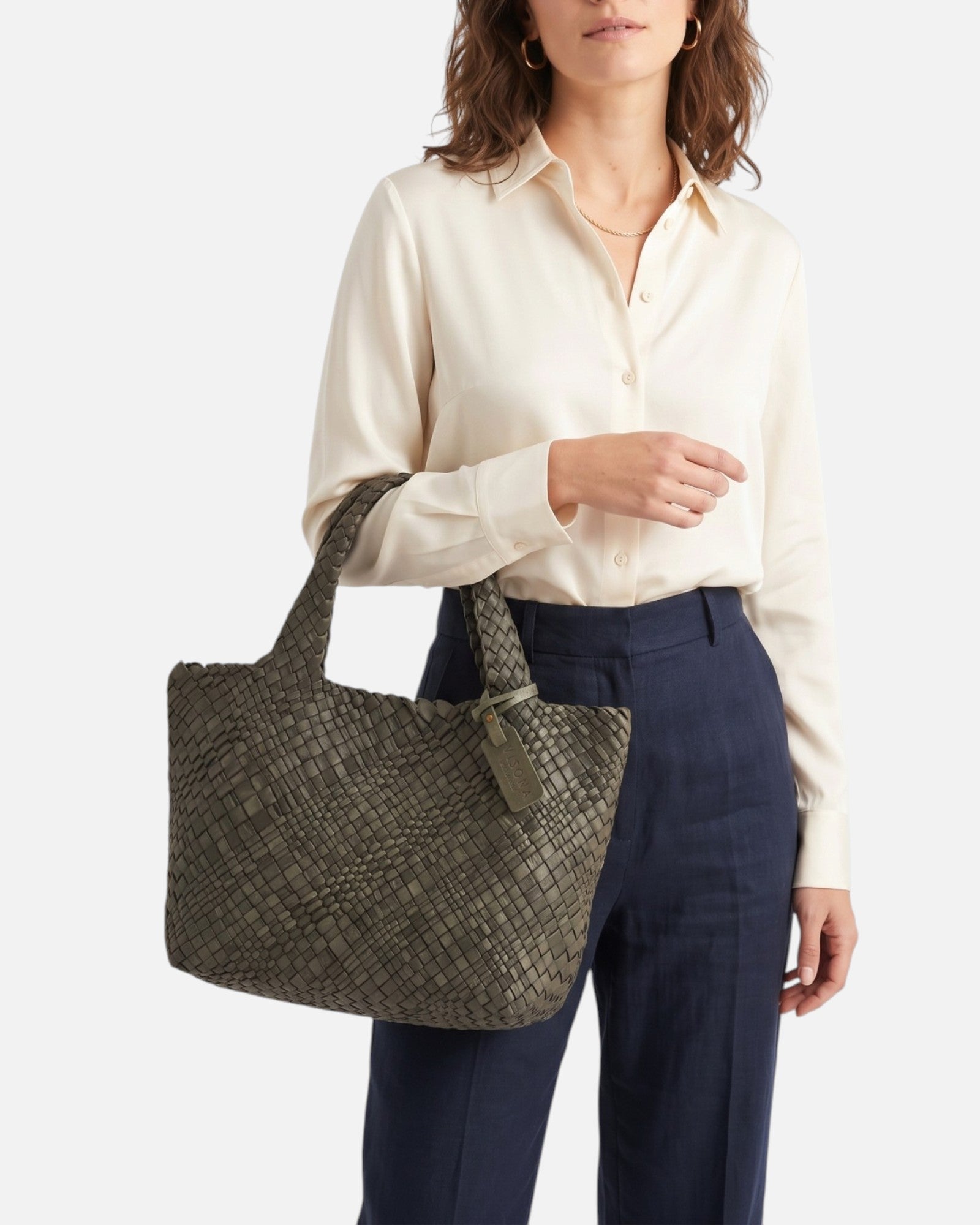 modelo luciendo en la mano el Bolso Tote Intrecciato Salvia de Plinio Visonà vistiendo blusa clara y pantalón marino.