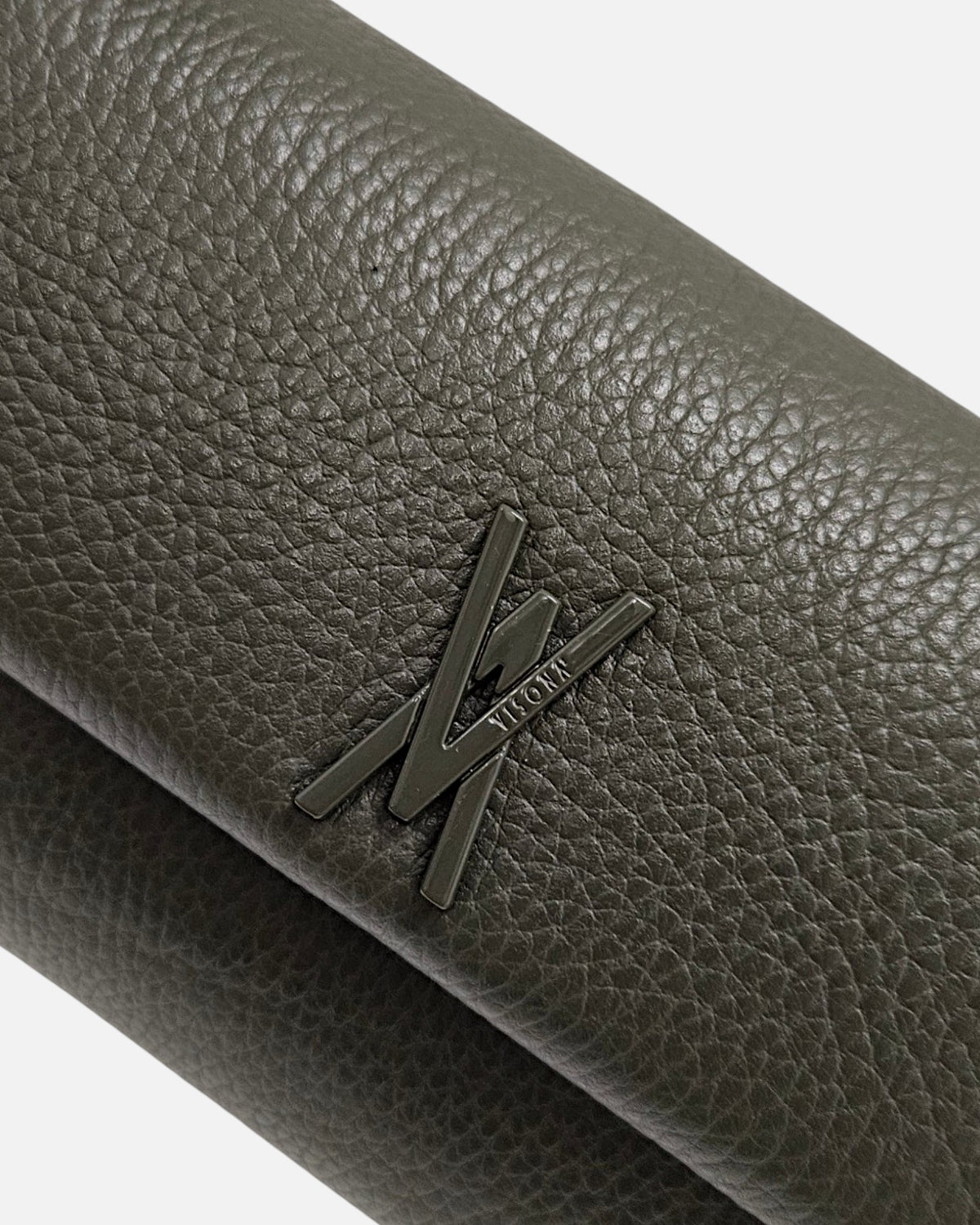primer plano macro del Bolso Bandolera Verde Musgo de Plinio Visonà, permitiendo apreciar la textura del grano de la piel y el aplique del logotipo.
