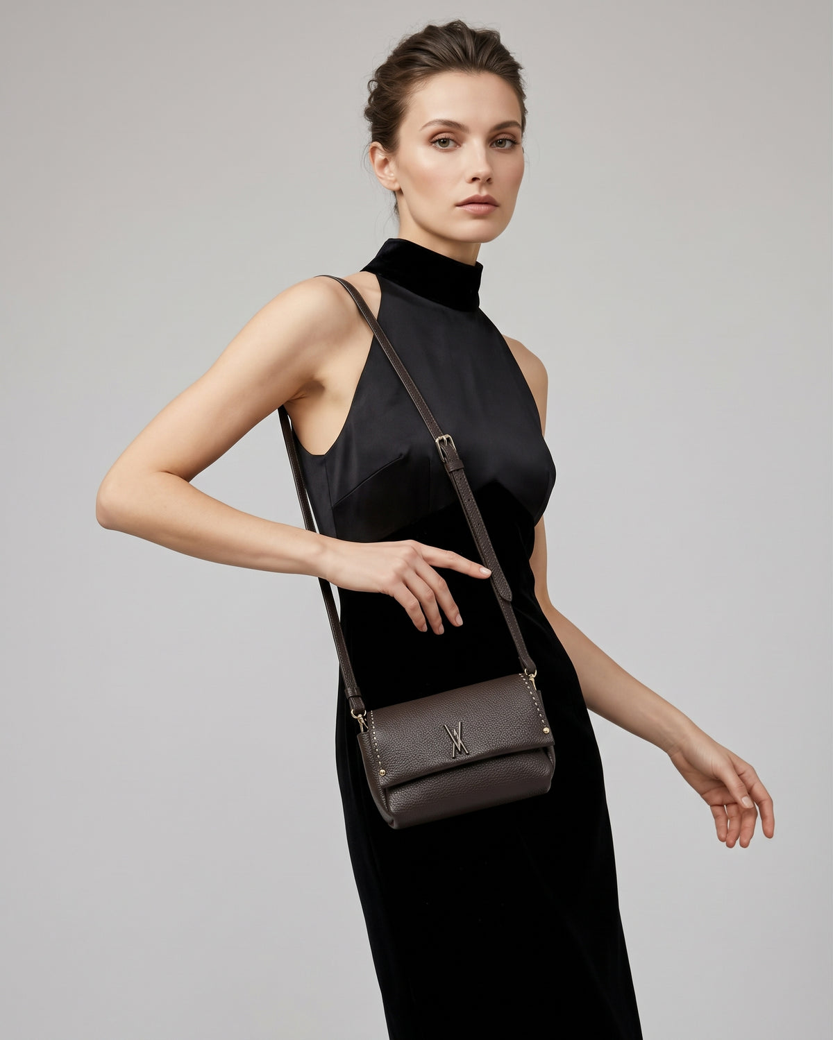 modelo luciendo colgado al hombro el Bolso Bandolera Cacao de Plinio Visonà sobre un elegante vestido negro.