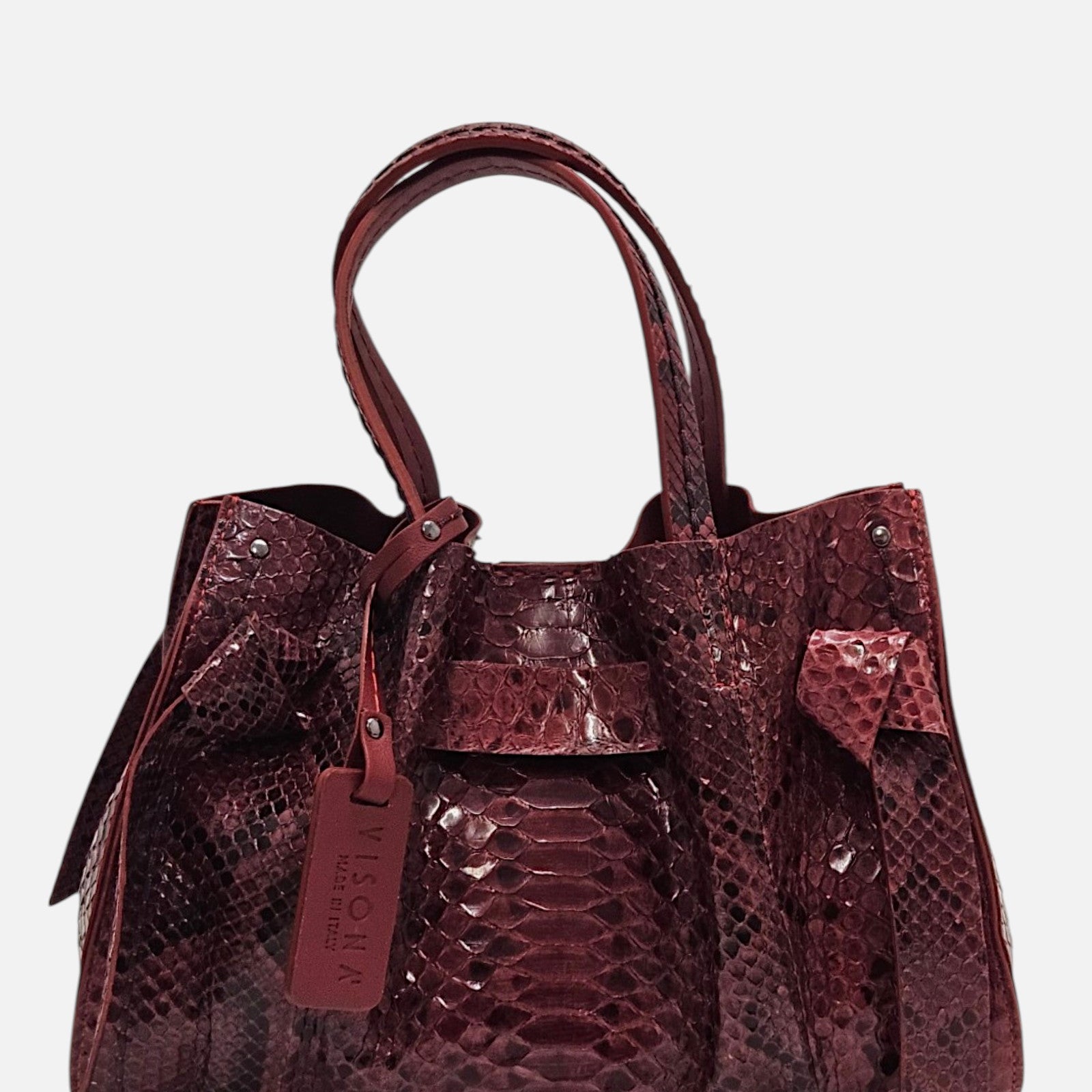 Bolso Pitón Pitagora Bordeus de Plinio Visonà en piel burdeos de grabado pitón con nudos laterales y etiqueta colgante.