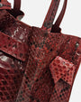 plano macro del grabado de escamas en piel burdeos y el detalle de la costura del nudo del Bolso Pitón Pitagora Bordeus de Plinio Visonà.