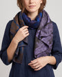 modelo luciendo el Foulard Viola de lana y seda anudado al cuello sobre un vestido azul marino.