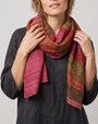 modelo luciendo el Foulard Riga Carmine anudado al cuello en bucle sobre una prenda oscura.   