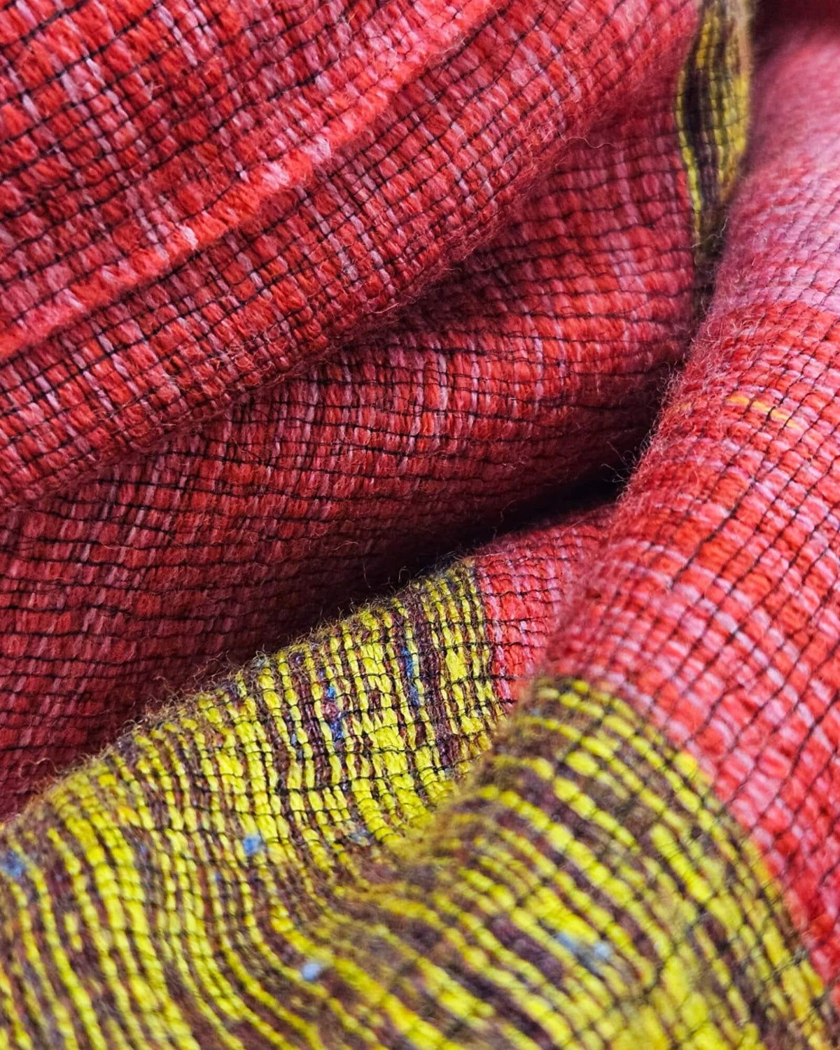 primer plano macro del entramado textil del Foulard Riga Carmine en tonos rojo, frambuesa y mostaza.